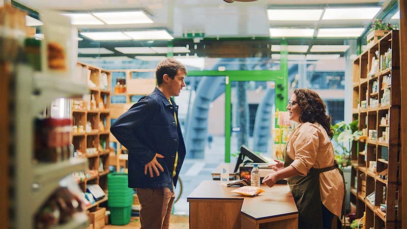 man in shop by till with hands on pockets