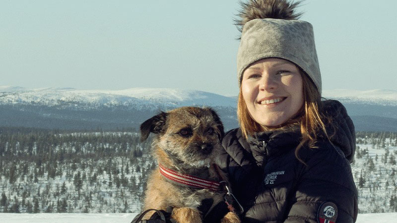 Anniina Kopperoinen holding a dog and smiling with snowy background